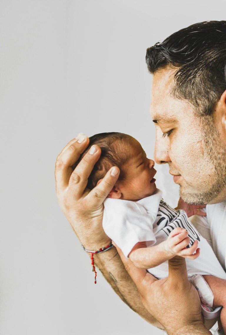 A touching portrait of a father gently holding his newborn baby, showcasing love and fatherhood.