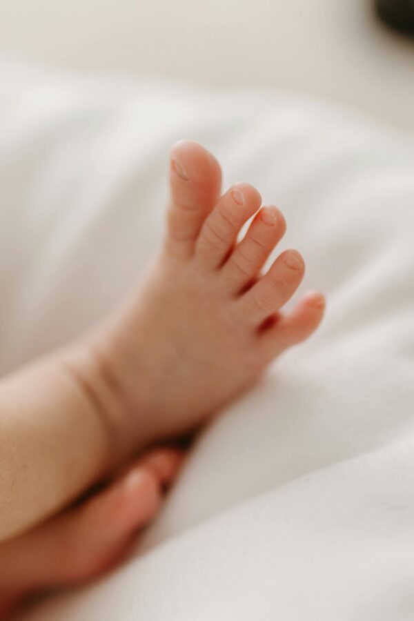 Adorable close-up of a baby's foot resting on soft, white bedding.