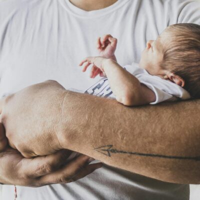 Capture of a newborn baby peacefully sleeping in protective arms, symbolizing love and care.