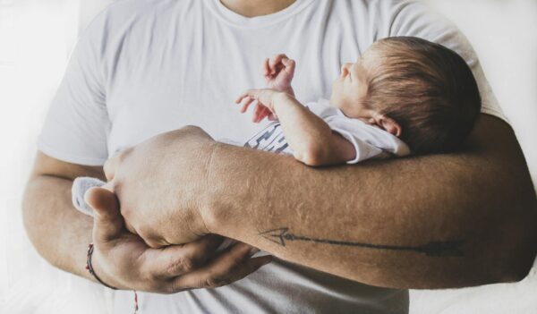 Capture of a newborn baby peacefully sleeping in protective arms, symbolizing love and care.