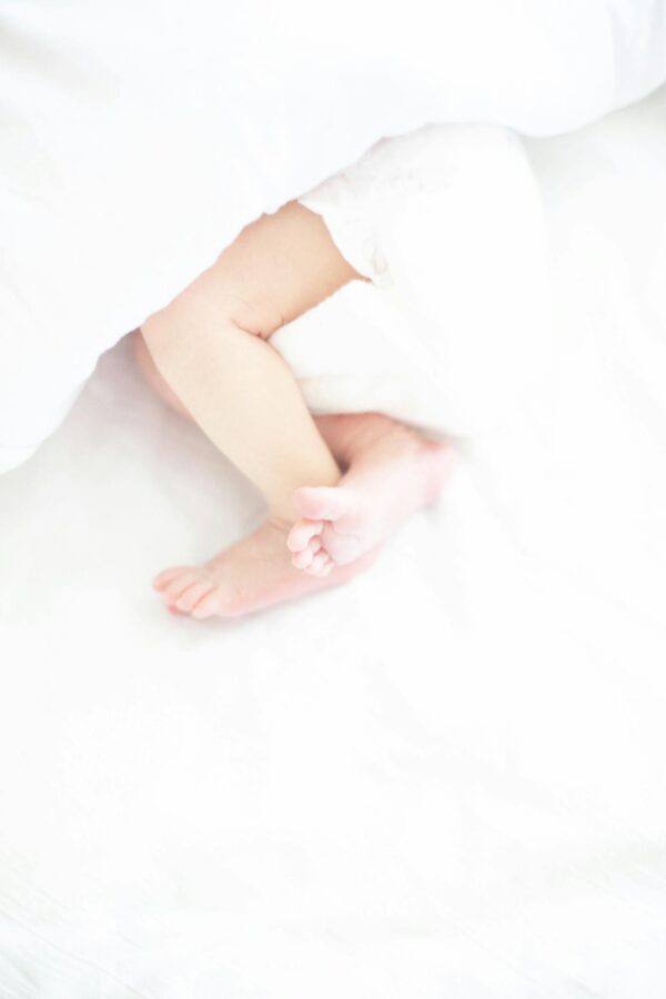 Close-up of a baby's feet peeking out from a white blanket, symbolizing innocence and comfort.