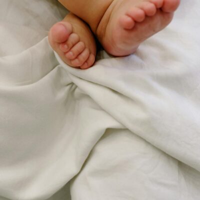 Close-up of cute baby feet crossed on a soft white blanket, capturing innocence and warmth.