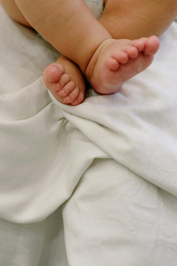 Close-up of cute baby feet crossed on a soft white blanket, capturing innocence and warmth.