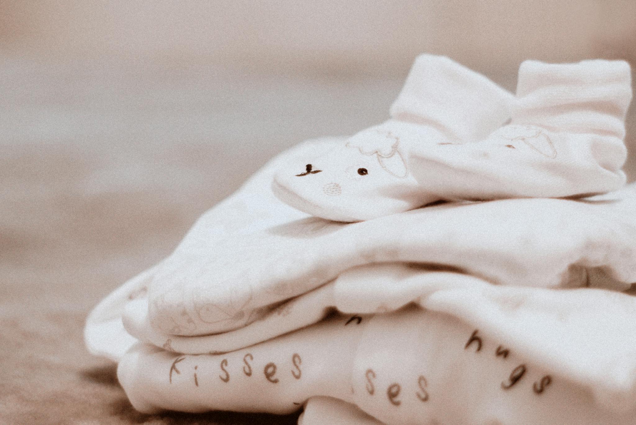 Close-up of soft white baby clothes with cute animal patterns, ideal for newborn comfort.